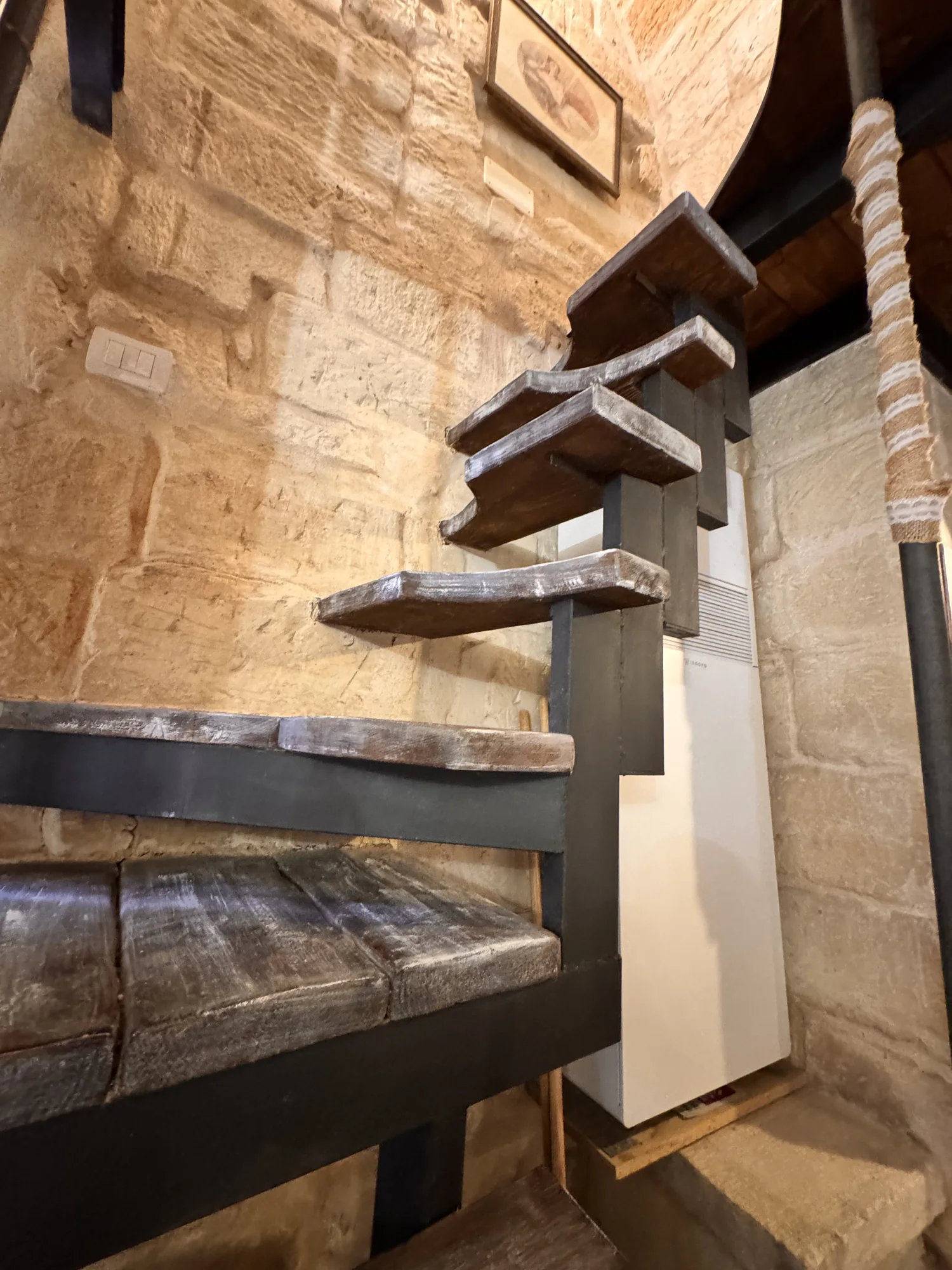 Gradini in legno della scala a chiocciola accanto alle pareti in pietra di Boemondo House