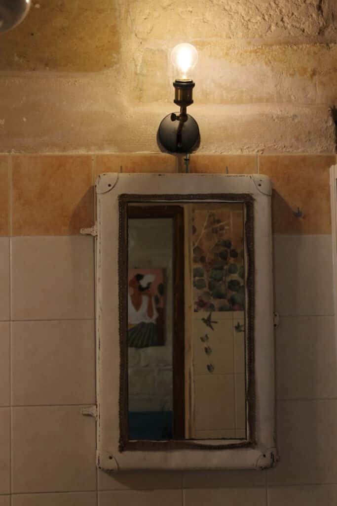 Specchio e lampada sopra il lavabo nel bagno di Boemondo House