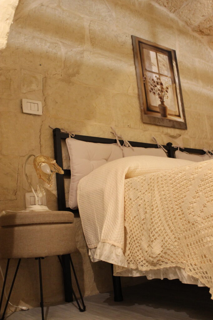 Letto matrimoniale e comodino nella camera sul soppalco di Boemondo House