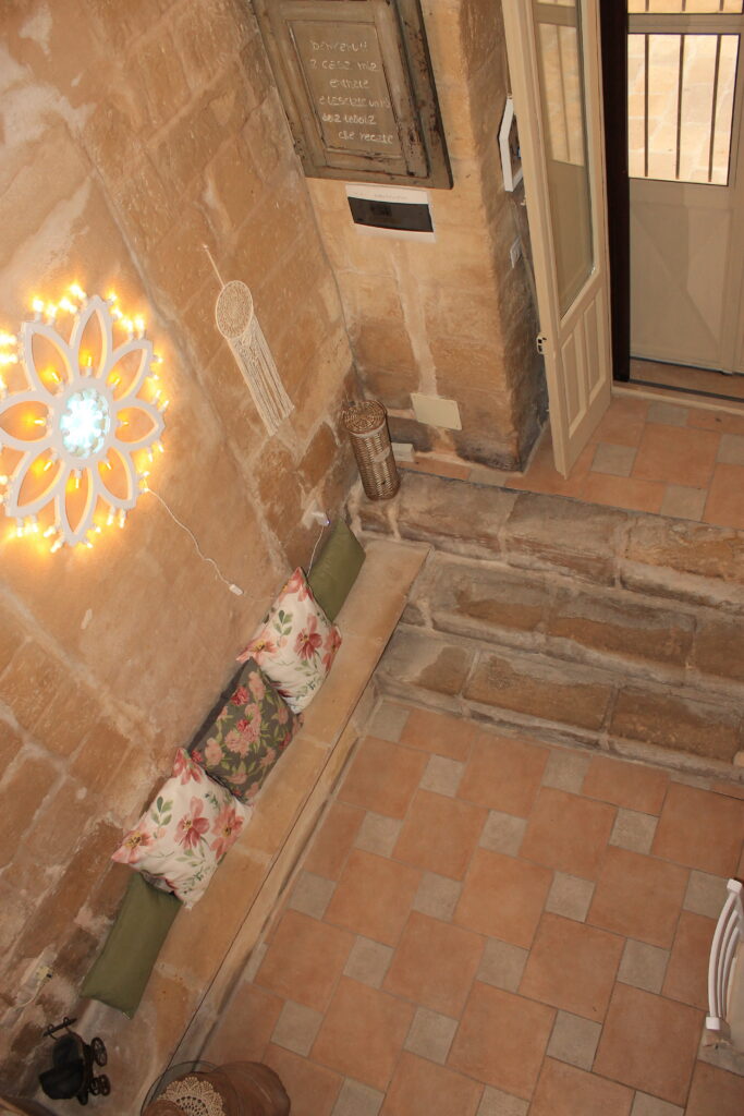 Vista dal soppalco sul soggiorno con gradini, seduta e luminaria di Boemondo House