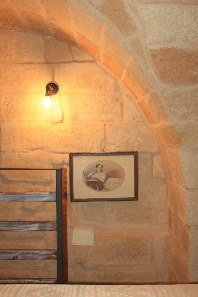 Volta in pietra e ringhiera del soppalco illuminate da una lampada a Boemondo House