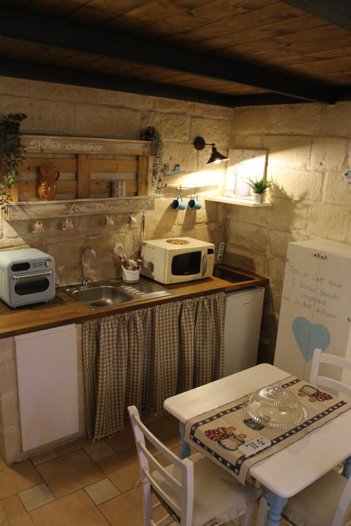 Cucina e tavolo da pranzo sotto il soffitto in legno del soppalco di Boemondo House